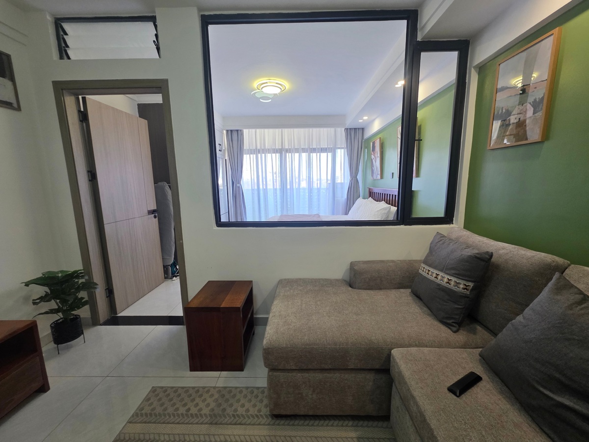 Living room with sofa, workspace and green accent wall